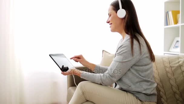 happy woman with tablet pc and headphones at home - Séquence, vidéo