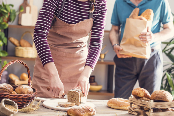 Руки женщины режут хлеб из цельного зерна
 - Фото, изображение