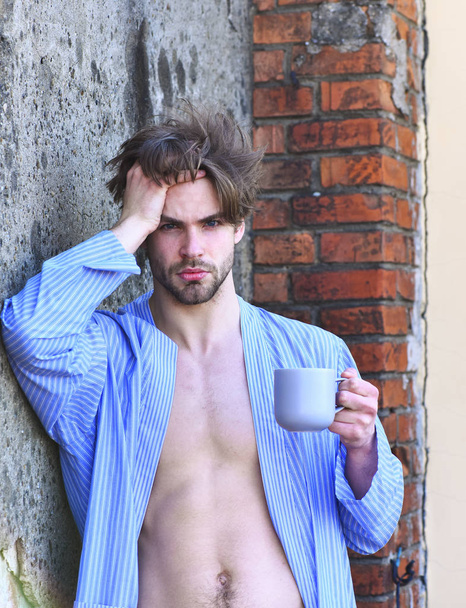 Caucasian macho in blue striped pajamas holding cup - Zdjęcie, obraz