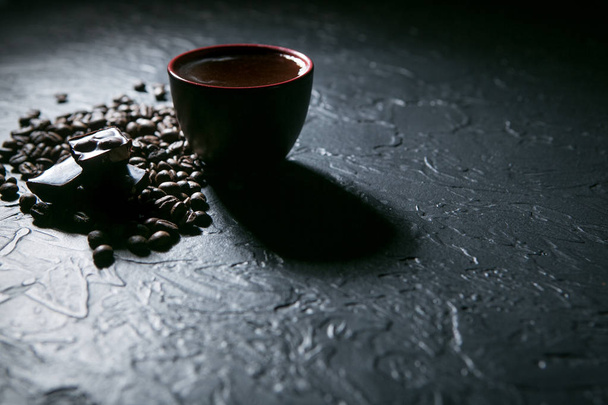 Kaffeetasse und Kaffeebohnen und Schokolade auf schwarzem Hintergrund - Foto, Bild