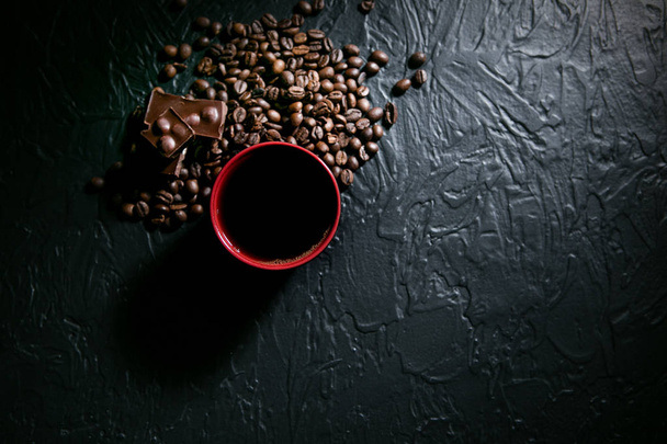 coffee cup and coffee beans and chocolate on black background - Fotoğraf, Görsel