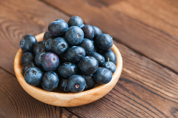 Close up of fresh raw blueberries served in a wooden plate. Wood - Foto, afbeelding
