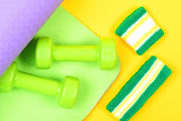 Dumbbells on green and purple mat for yoga and sweatband - Фото, изображение