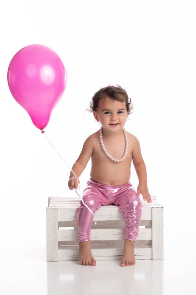 Sonriente niña de un año con globo rosa
 - Foto, imagen