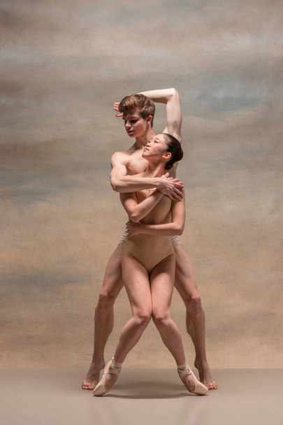 Ζευγάρι χορευτών μπαλέτου που παρουσιάζουν πάνω από γκρίζο φόντο - Φωτογραφία, εικόνα