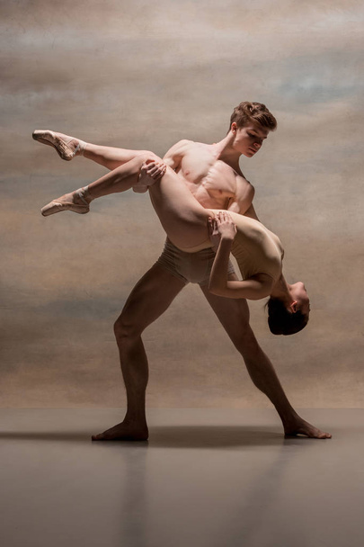 Couple of ballet dancers posing over gray background - Foto, imagen