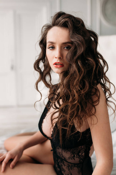 Beautiful brunette model with perfect body sitting on a bed in black lace underwear. - Fotografie, Obrázek