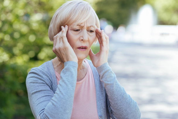 Worried pensioner having headache outdoors - Fotó, kép