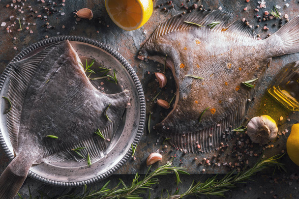 Two raw flounders with different seasoning on the stone background top view - 写真・画像