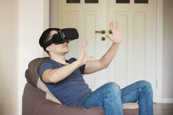 Ο άνθρωπος παίζει παιχνίδι με γυαλιά εικονικής πραγματικότητας σε εσωτερικούς χώρους - Φωτογραφία, εικόνα