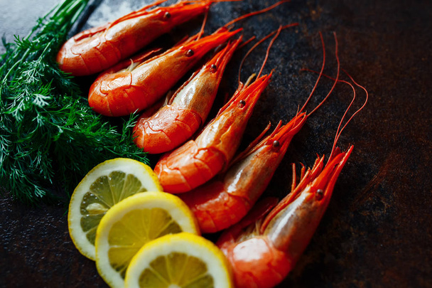 Shrimps with lemon and greens on a dark background - Foto, immagini