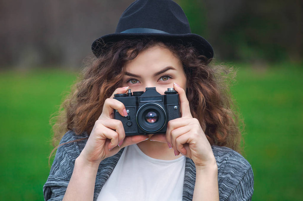 schöne Fotografin mit lockigem Haar hält eine Kamera und macht ein Foto - Foto, Bild