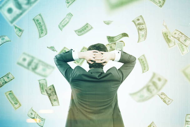 Man with hands behind his head in a money flow - Фото, изображение