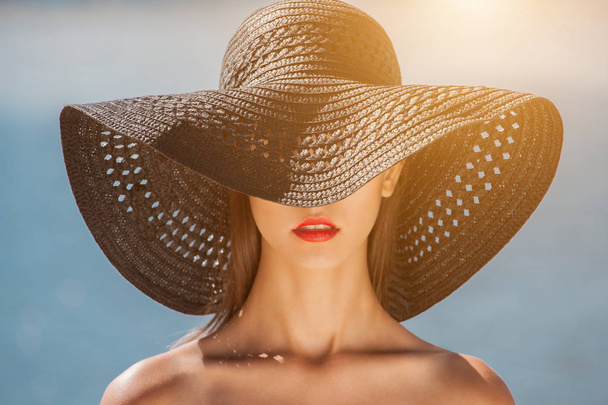 Приваблива дівчина в чорному капелюсі носить на голові, на пляжі
 - Фото, зображення