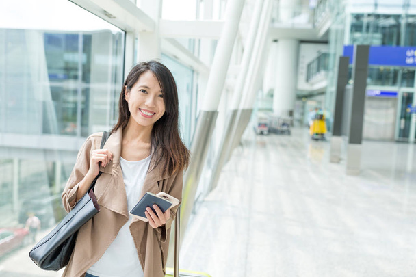 Жінка тримає мобільний телефон в аеропорту
 - Фото, зображення