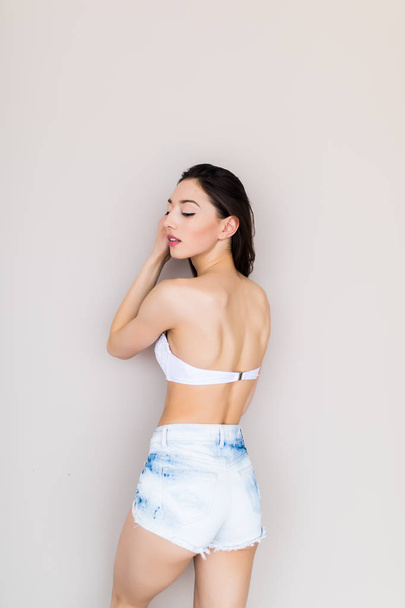 Beautiful woman wearing jeans shorts and bra isolated - Photo, Image