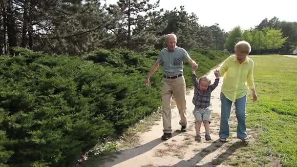 Бабушка и дедушка поднимают мальчика на свежем воздухе
 - Кадры, видео