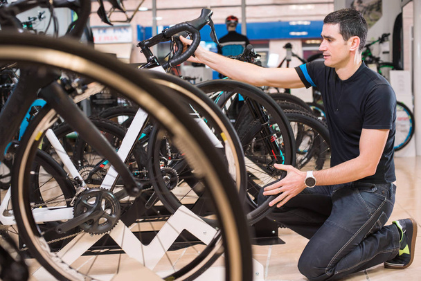 Young male master is concentrated on repairing the bicycle in a special workshop - Φωτογραφία, εικόνα