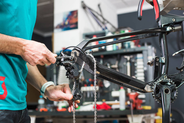 Fechar as mãos masculinas fixando o mecanismo de corrente da bicicleta em uma loja especial
 - Foto, Imagem