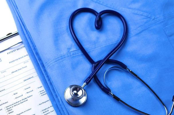 Stetoskop lekarskie skręcone w kształcie serca, leżącego na liście historię choroby pacjenta i lekarza niebieski jednolite zbliżenie - Zdjęcie, obraz