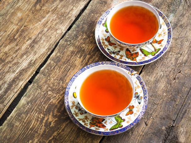 Чашка чая, чайник и чайные пакетики на деревянном столе крупным планом
 - Фото, изображение