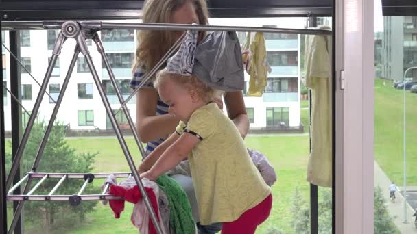 Little girl helping her mother woman to hang washed laundry - Footage, Video