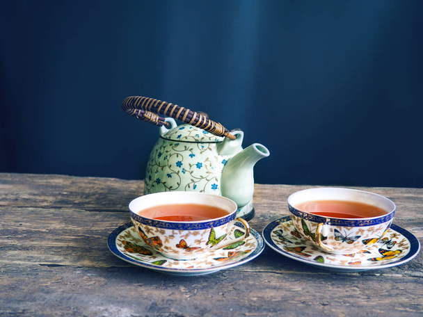 filiżankę herbaty, czajnik i torebki herbaty na drewniany stół szczegół - Zdjęcie, obraz