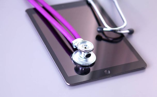 Tablet computer with a stethoscope lie on a table - Photo, image