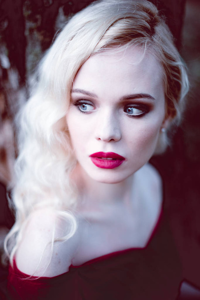 Mode prachtige jonge blonde vrouw in mooie rode jurk in een sprookjesachtige forest. magische sfeer. toning schot - Foto, afbeelding