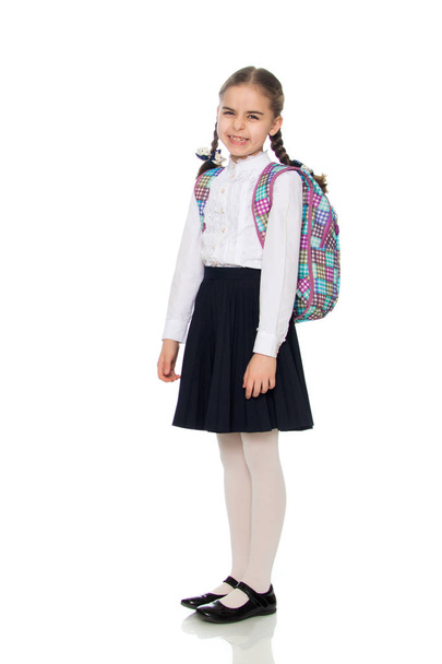 Beautiful schoolgirl with a backpack behind her shoulders. - Фото, изображение