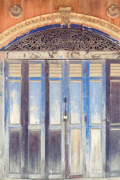 Ρουστίκ ξύλινες Πτυσσόμενες πόρτες μπροστά από το κλασικό Σινο-πορτογαλική αρχιτεκτονική shophouse κτίριο στην απαγόρευση Singha Tha, παλιά ιστορική περιοχή της Ουτάι Τάνι επαρχία στη βορειοανατολική περιοχή της Ταϊλάνδης - Φωτογραφία, εικόνα