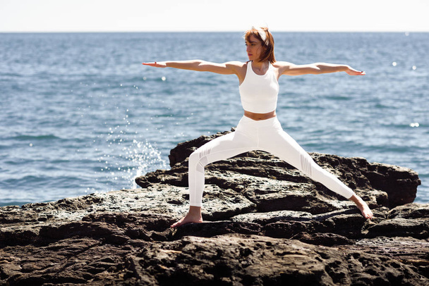 Jovem fazendo ioga na praia vestindo roupas brancas
 - Foto, Imagem