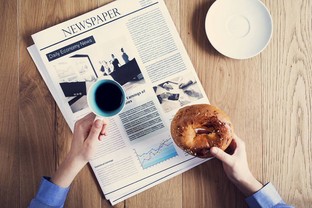 Vrouwelijke handen met gebak met het lezen van de krant - Foto, afbeelding