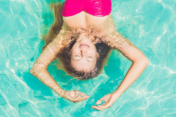 Beautiful young woman floating in pool - Фото, зображення