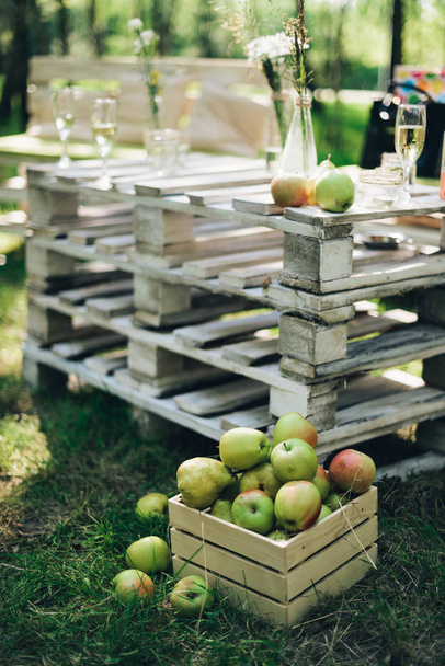 maçãs verdes em uma caixa perto de uma mesa caseira em madeira
 - Foto, Imagem