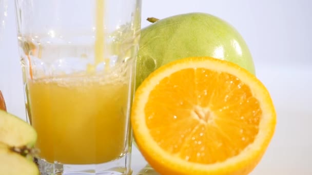 Orange juice pouring in glass on color background - Materiaali, video