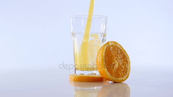 Orange juice pouring in glass on color background - Πλάνα, βίντεο