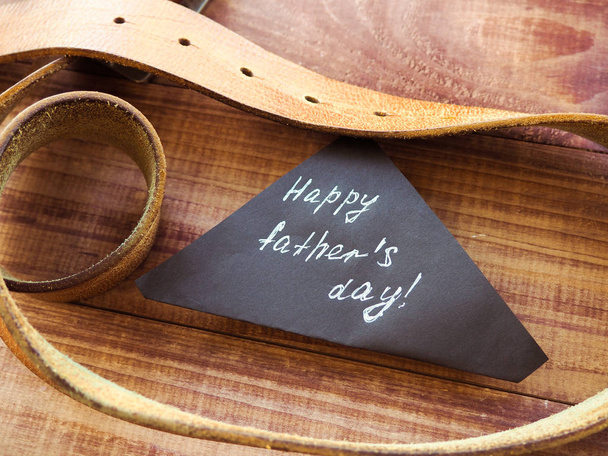 Feliz Día del Padre la correa de cuero sobre fondo de madera. Saludos y regalos
 - Foto, Imagen
