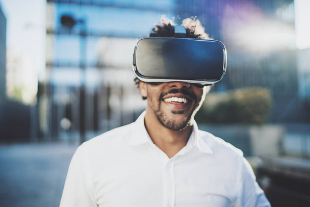 Concept of technology,gaming,entertainment and young people.Smiling american african man enjoying virtual reality glasses or 3d spectacles.Blurred background.Horizontal. - Foto, afbeelding