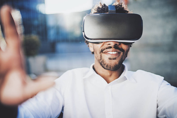 Concept of technology,gaming,entertainment and young people.Smiling american african man enjoying virtual reality glasses.Blurred background.Horizontal. - Photo, Image