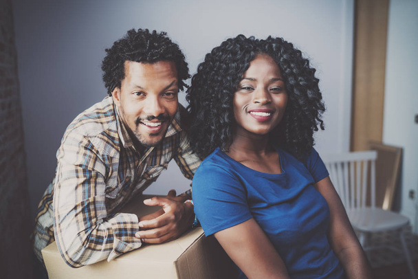 Happy young black african couple moving boxes into new apartment together and making a beautiful life.Cheerful family sitting in empty new home.Horizontal.Blurred background.Cropped. - Foto, immagini