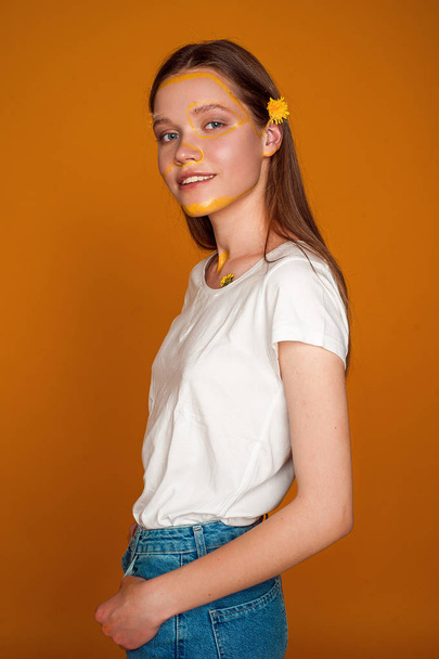 Girl with flowers on the yellow background - Foto, afbeelding