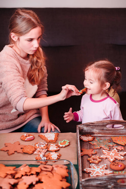 Sisters tasting Christmas gingerbread cookies - Foto, Imagen