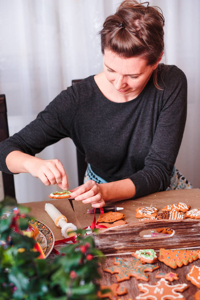 Woman decorating Christmas gingerbread with frosting - Valokuva, kuva