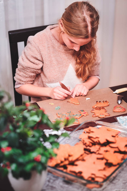 Girl decorating Christmas gingerbread cookies - Фото, изображение