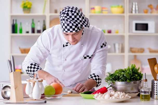 Νεαρός μάγειρας που εργάζεται στην κουζίνα - Φωτογραφία, εικόνα