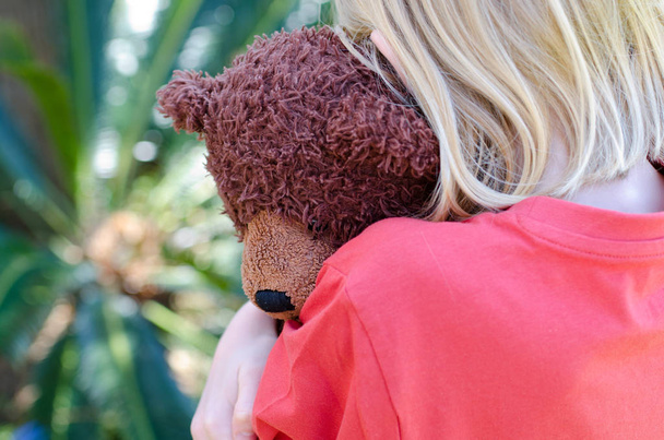 Klein meisje haar bruin teddy knuffelen sluiten - Foto, afbeelding