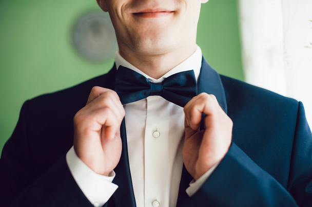 The groom in a suit holding a butterfly accessory in hands - Fotografie, Obrázek