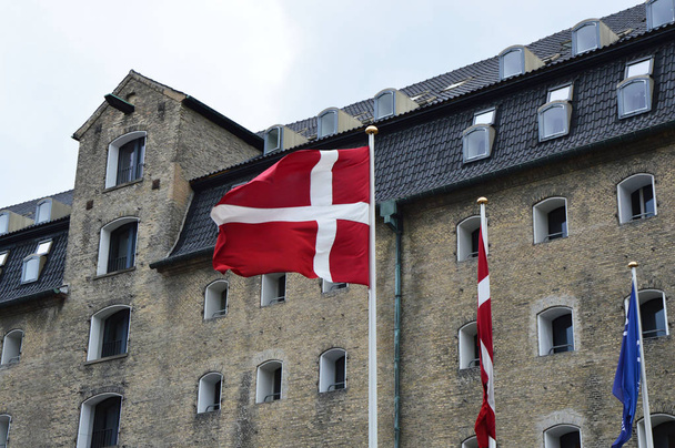 Bandiera danese che sventola sullo sfondo con l'Admiral Hotel, Copenaghen, Danimarca
 - Foto, immagini