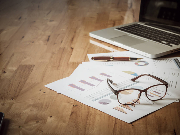 brýle a laptop a finanční papírování na dřevěný stůl v - Fotografie, Obrázek